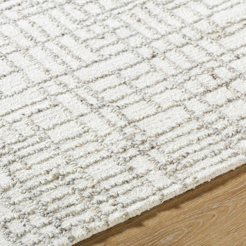 Close-up of the hand-tufted Tibby Area Rug. Light silver and silver gray wool rug with a geometric pattern. Texture