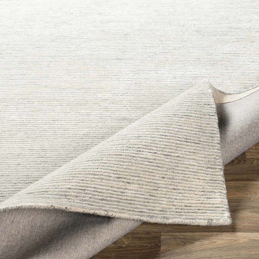 Close-up of the Orcas Hand Tufted Wool-Blend Rug in Aqua, showing cream and gray stripes and hand-tufted texture. Fold