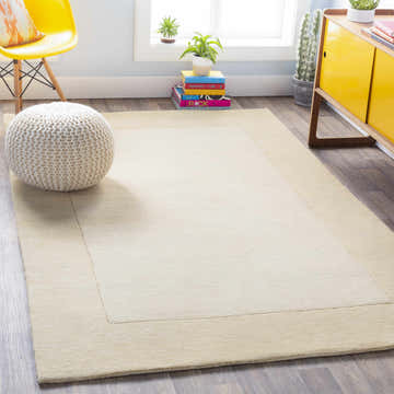 Bright living room scene with a Bordered Solid Wheat Cream Wool Rug, yellow chair, and white pouf. Roomscene-Rectangle