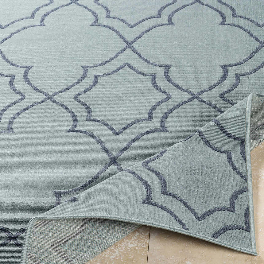 Close-up of Ursa Area Rug in pale blue and navy, featuring a geometric trellis pattern and machine-woven texture. Fold