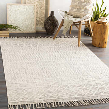 Living room scene with Valyermo Beige hand woven cotton rug, chair with throw pillow, wood stump table, and neutral wall art. Roomscene-Rectangle