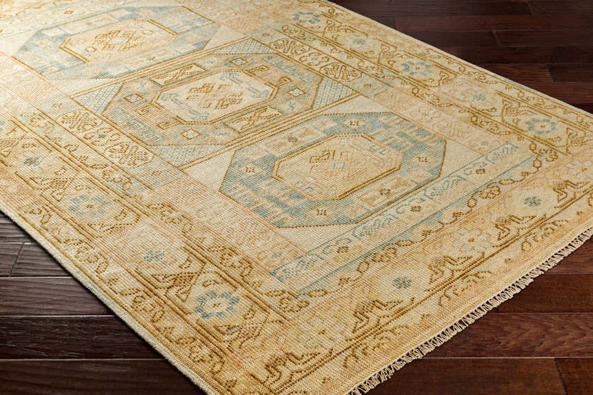 Close-up of the hand-knotted Villareal Area Rug, a traditional design in cream, beige, and ice blue on dark wood floors. Corner