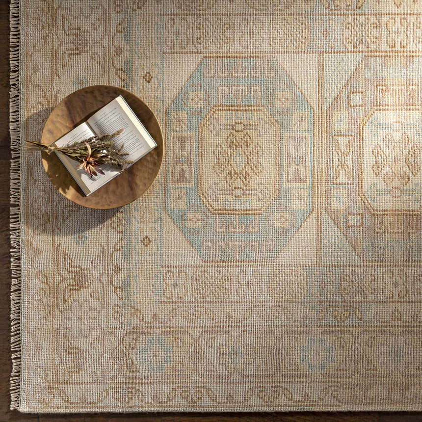 Close-up of the hand-knotted Villareal Area Rug in cream, dusty pink, ice blue, and beige with a traditional Oriental pattern. Styleshot