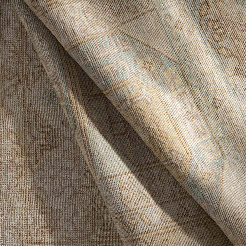 Close-up of the hand-knotted Villareal Area Rug showing its cream, beige, and ice blue traditional pattern and wool texture. Fold