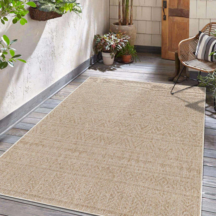 Covered porch with a light peach Vanderhoof Indoor Outdoor Rug, wicker chair, plants, and wood door. Roomscene-Rectangle