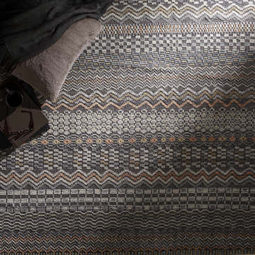 Close-up of the Verdigris Premium Rug. Charcoal, ice blue, light gray, and peach tones in a geometric, hand-knotted design. Styleshot