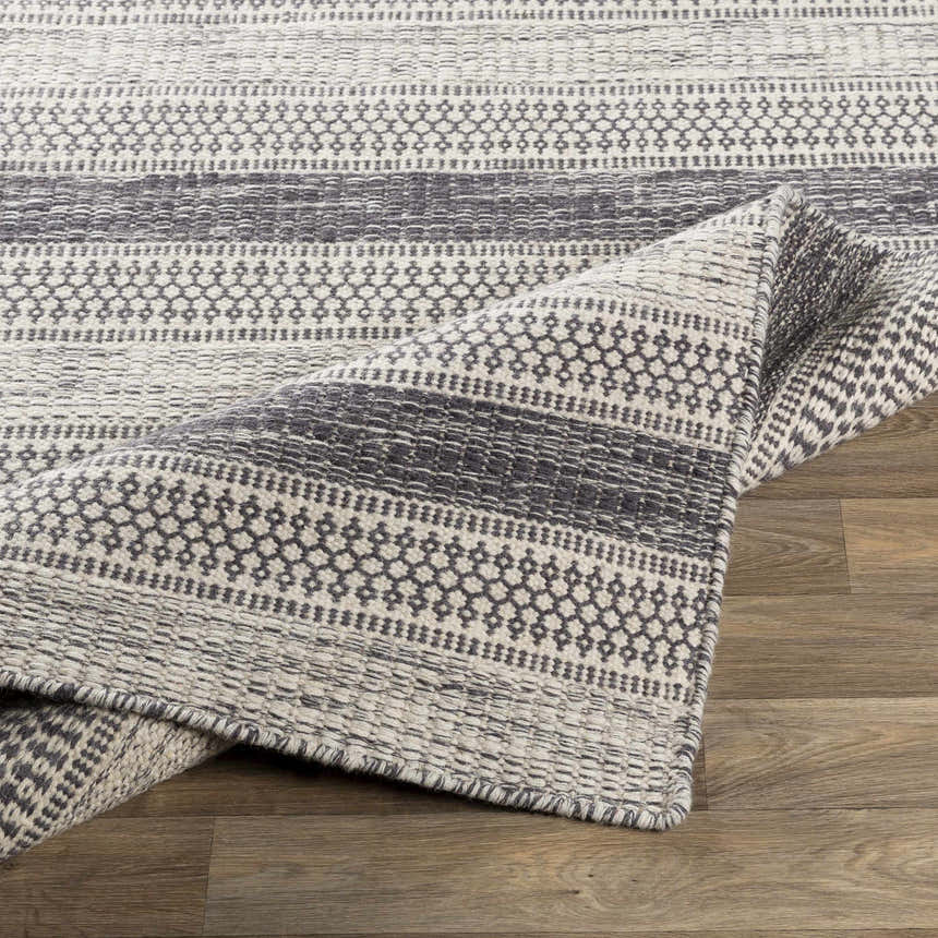 Close-up of the hand woven Vernonia Area Rug. Black and ivory wool rug with a contemporary striped pattern. Fold