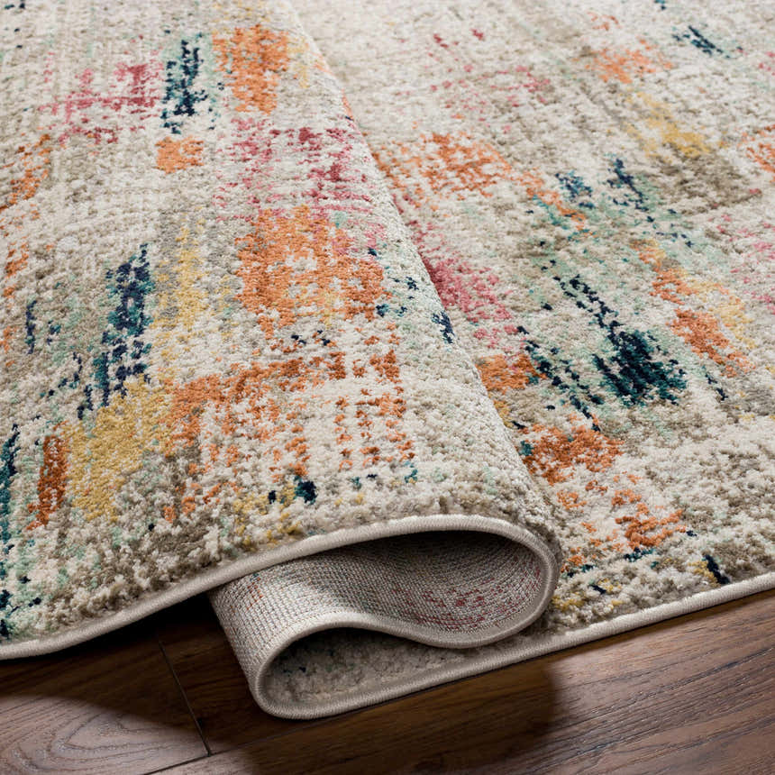 Close-up of the Eversley Area Rug showing its cream base and abstract design with dark blue, pink, and mustard accents. Fold