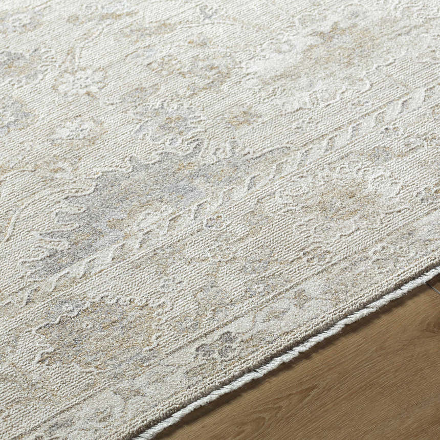 Close-up of the Vaman Luxe Rug. Light silver and sterling gray tones with a traditional, subtle floral pattern. Machine woven texture. Texture