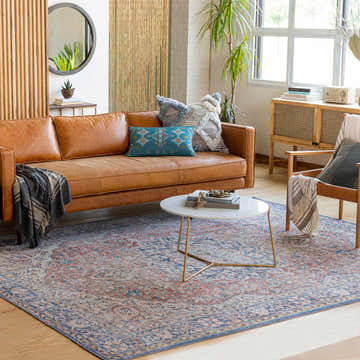Living room scene with a brown leather sofa and Wacousta Red&Blue Washable Rug, creating a warm, inviting space. Roomscene-Rectangle