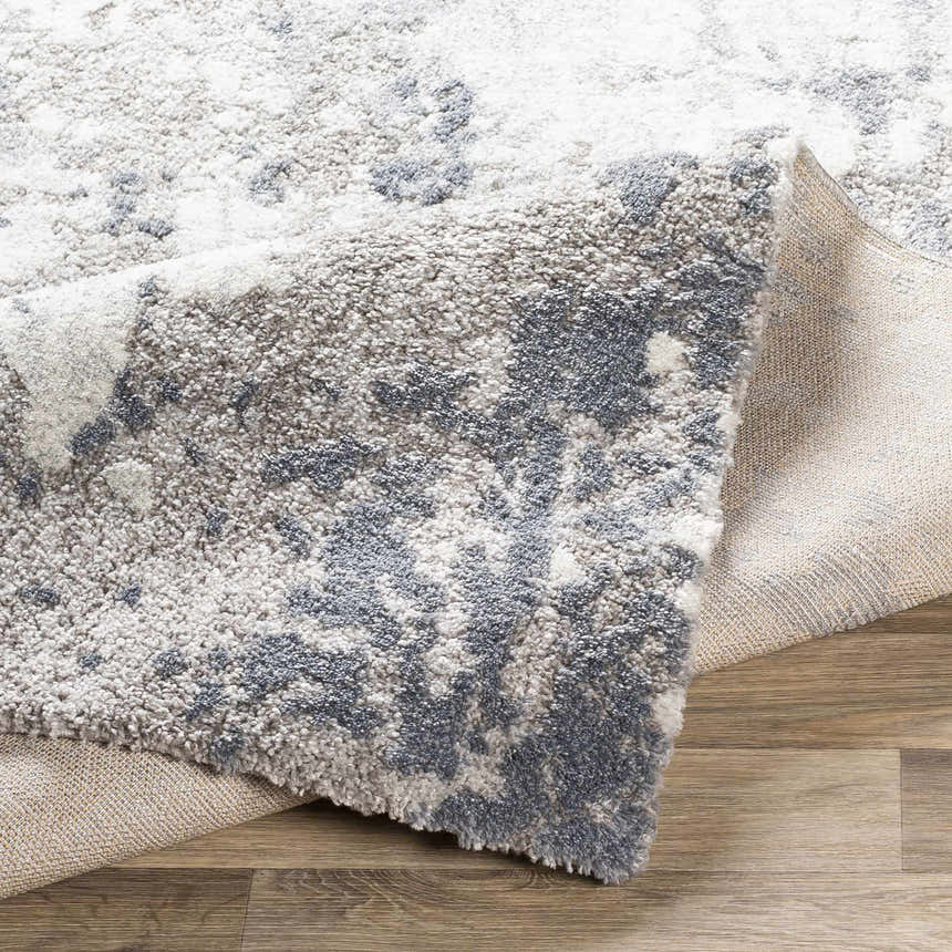 Close-up of the Walhonding Area Rug, a contemporary design in denim, ivory, and gray. Machine-woven texture detail. Fold