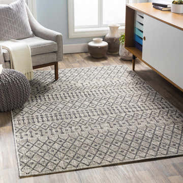 Living room scene with a gray armchair and the Wallkill Area Rug in black, charcoal, taupe, and white. Roomscene-Rectangle