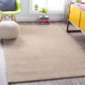 Living room scene with a solid tan Brockton wool rug, green chair, knit pouf, and yellow cabinet. Roomscene-Rectangle