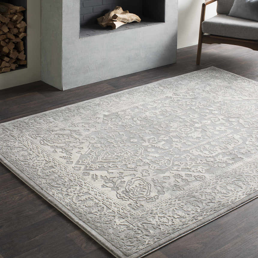Living room scene with a gray Watford Updated Traditional Tibetan Rug, fireplace, dark wood floors, and gray chair. Roomscene-Rectangle