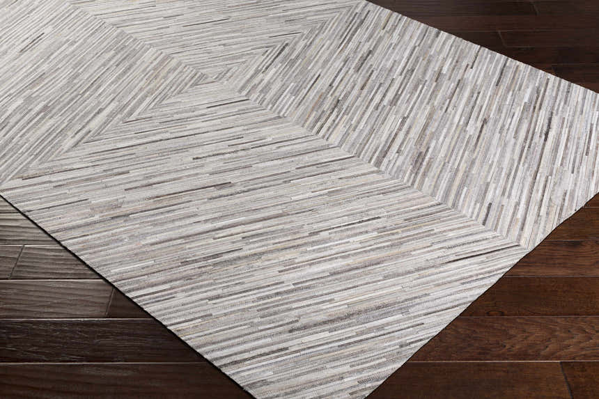 Close up of Wauzeka Premium Area Rug showing cream, brown and gray tones with a geometric pattern on dark wood floor. Corner