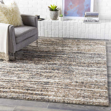 Living room scene with gray chair and Weddin Striped Plush Area Rug in charcoal, cream, gray, light gray, and tan. Roomscene-Rectangle