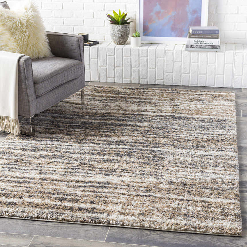 Living room scene with gray chair and Weddin Striped Plush Area Rug in charcoal, cream, gray, light gray, and tan. Roomscene-Rectangle