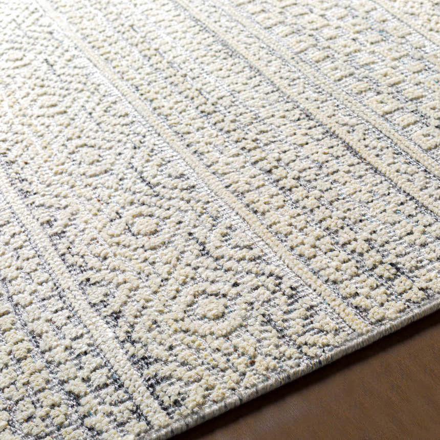 Close-up of the hand-knotted Wessington Area Rug. Cream, light and medium gray, and navy colors in a geometric, textured design. Front