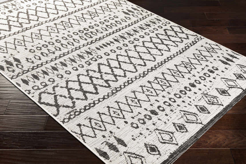 Close-up of the Westside Outdoor Area Rug. Black and white rug with a bohemian-inspired geometric pattern. Corner