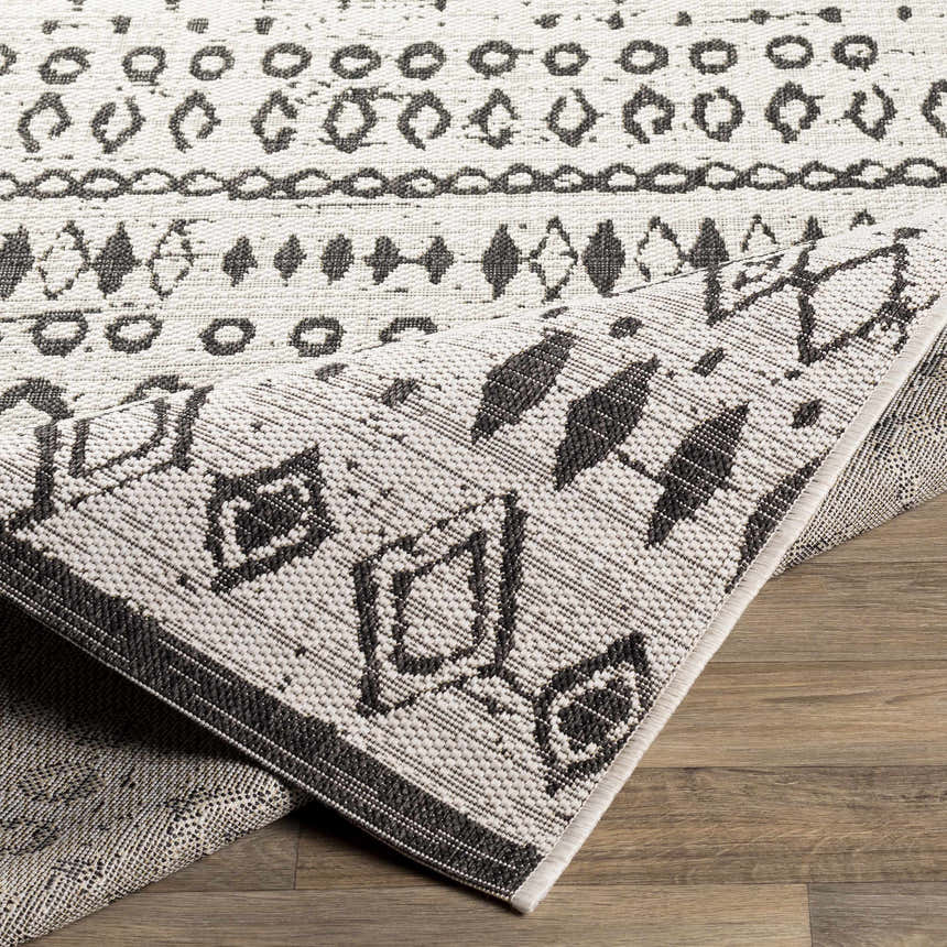 Close-up of the Westside Outdoor Area Rug showcasing its black and white bohemian-inspired geometric pattern and textured weave. Fold