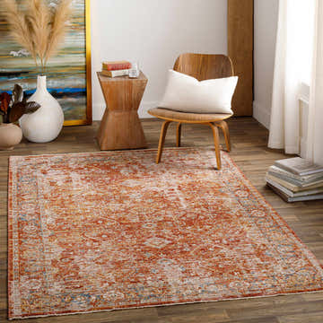 Living room scene with a rust-colored Wetaskiwin Area Rug, wood floors, chair with pillow, and decorative accents. Roomscene-Rectangle