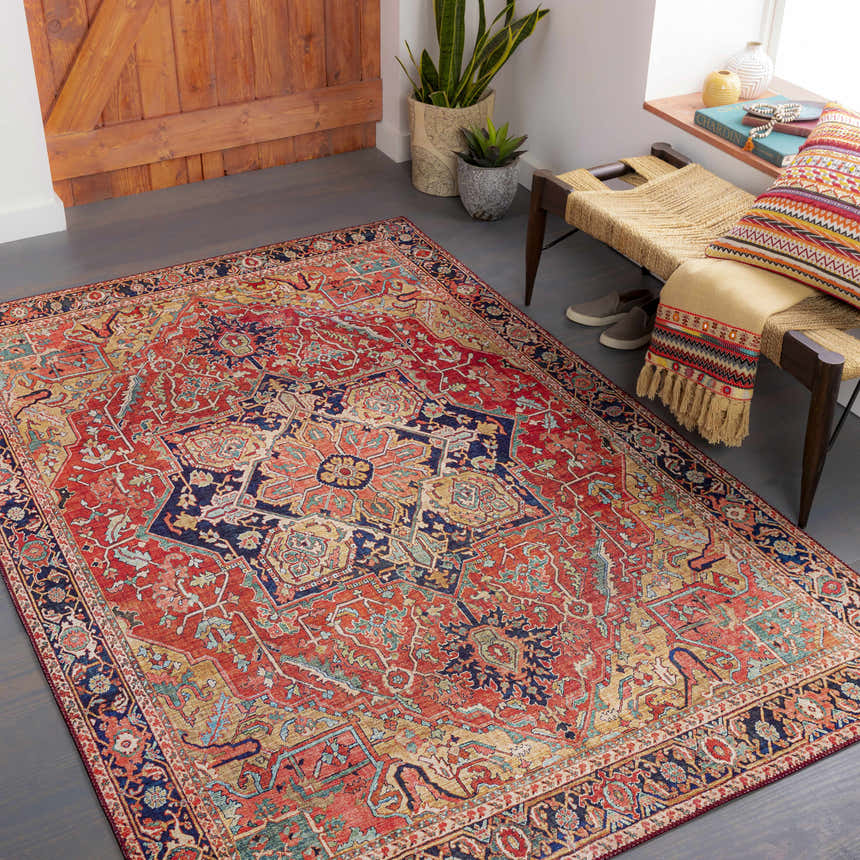 Entryway with a brick red and navy Whittingham Area Rug, woven bench, wood door, and plants. Roomscene-Rectangle