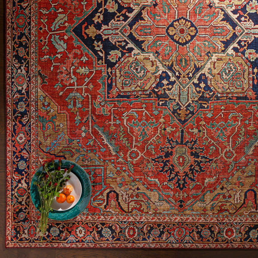 Close-up of the Whittingham Area Rug, showcasing its brick red, cream, and navy bohemian-style pattern and soft polyester texture. Styleshot