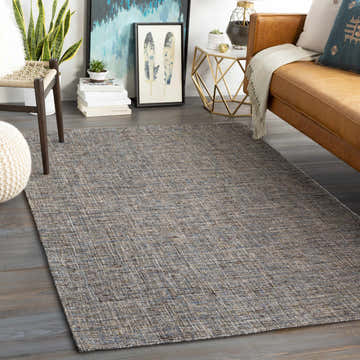 Living room scene with a brown leather couch and the amber and blue Wilbar Area Rug. Roomscene-Rectangle