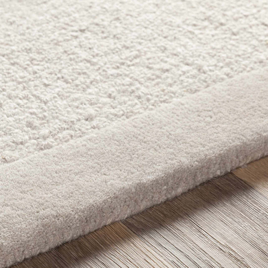Close-up of the hand-tufted Winooski Area Rug. Cream and light gray wool rug with a solid, striped design and a textured surface. Texture