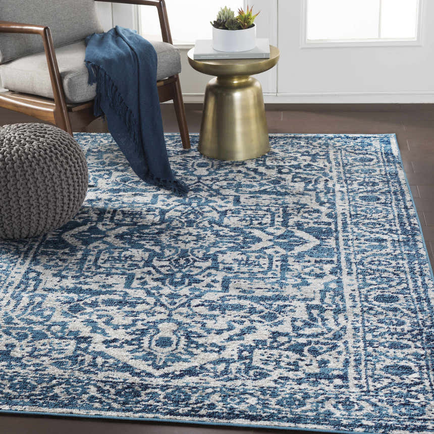 Living room scene with a blue and white Wellsblue Traditional Rug, gray chair, and brass side table. Roomscene-Rectangle