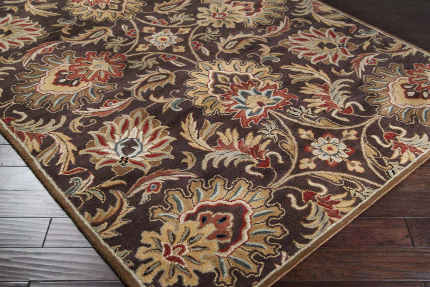 Close-up of the hand-tufted Chesterton 1028 brown wool rug. Features a traditional floral pattern in brown, red, beige, and sage. Corner