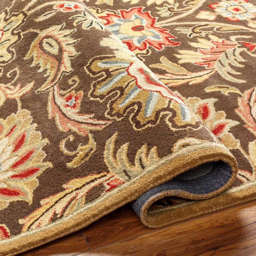Close-up of the hand-tufted Chesterton 1028 brown wool rug. Features a traditional floral design in brown, red, beige, and gray tones. Fold