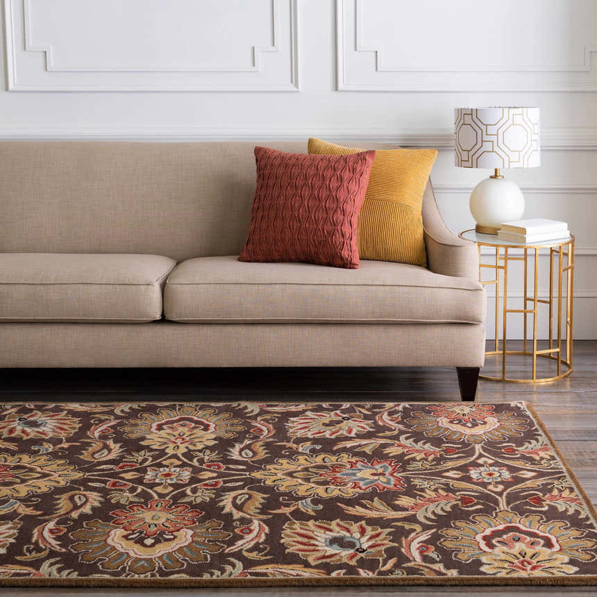 Living room scene with a Chesterton 1028 brown wool rug, beige sofa, brick red and gold pillows, and a gold side table. Roomscene-Rectangle