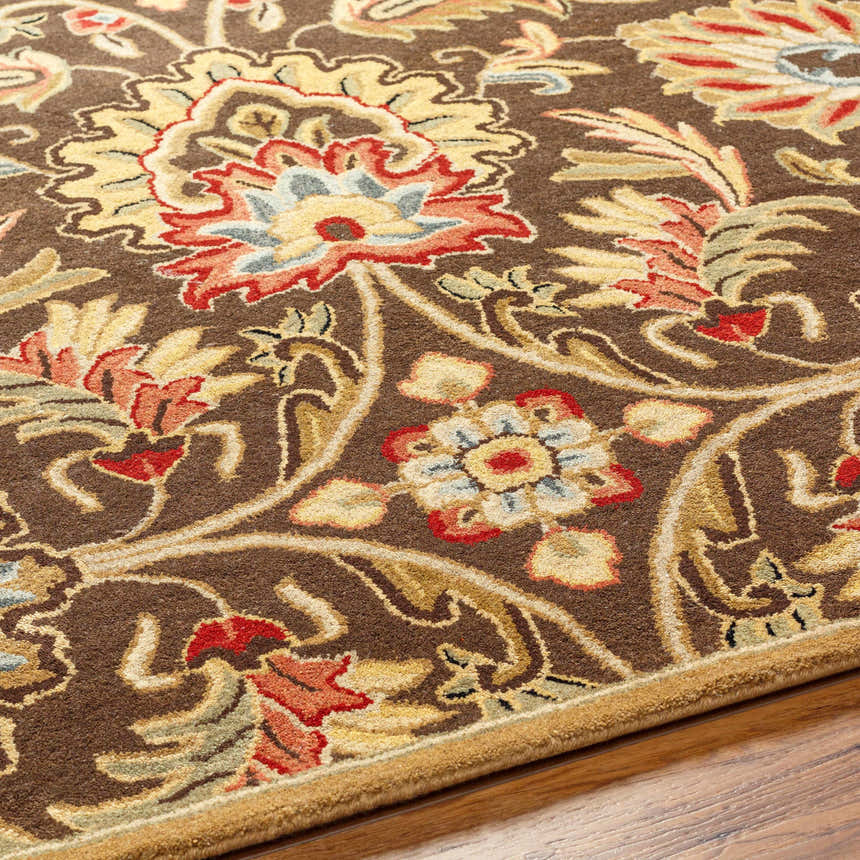 Close-up of the hand-tufted Chesterton 1028 brown wool rug. Features a traditional floral pattern in brown, red, and beige tones. Texture