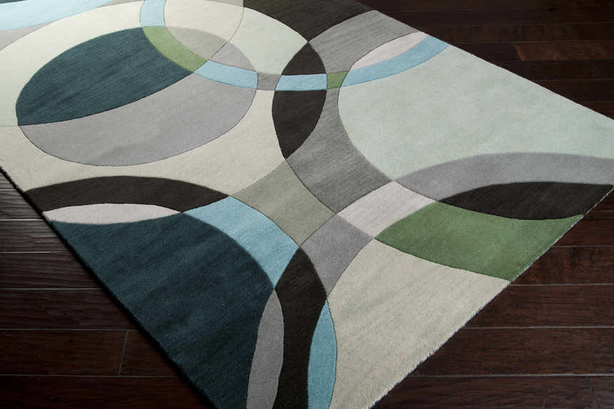 Close-up of the hand-tufted Wyocena Wool Rug. Contemporary design with aqua, black, gray, and green circles. Corner