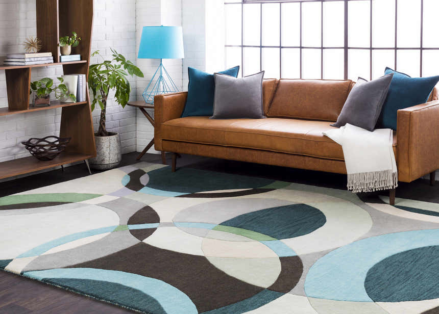 Living room scene with a brown leather sofa and the Wyocena Wool Rug in aqua, gray, and green geometric pattern. Roomscene-Rectangle