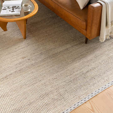 Living room scene with a Yaniklar Beige flat woven wool rug, tan leather sofa, and wood coffee table. Roomscene-Rectangle