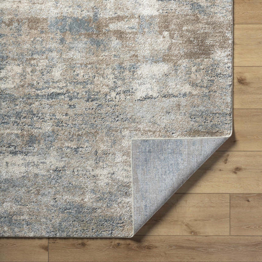 Close up of Yoshe Thick Luxe Rug showing beige, gray, and tan abstract pattern and rug backing. Fold
