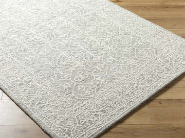 Close-up of the hand-tufted Yadid Gray Wool Area Rug featuring a traditional light silver and gray pattern. Corner