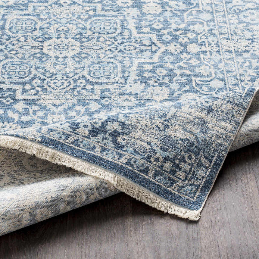 Close-up of the Yorkana Distressed Blue Rug showing its traditional, vintage-inspired pattern and fringed edge. Fold