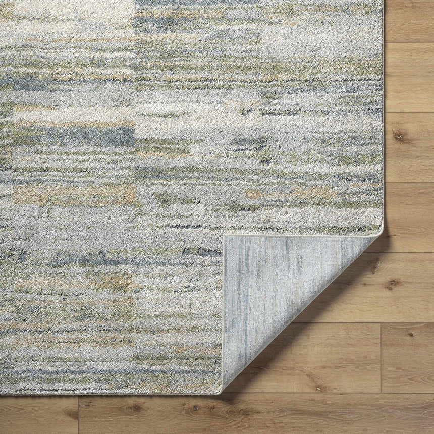 Close-up of the Yancy Thick Luxe Rug showing its beige, gray, olive, and tan contemporary design and machine woven texture. Fold