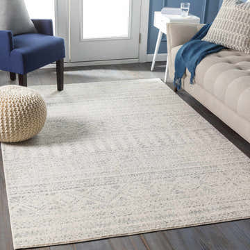 Living room scene with a gray and white Zarephath Area Rug, blue chair, and beige sofa. Roomscene-Rectangle