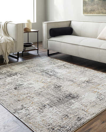 Living room scene with Zasha Area Rug in charcoal, ivory, mustard, peach, and tan colors. Modern sofa and wood floors. Roomscene-Rectangle