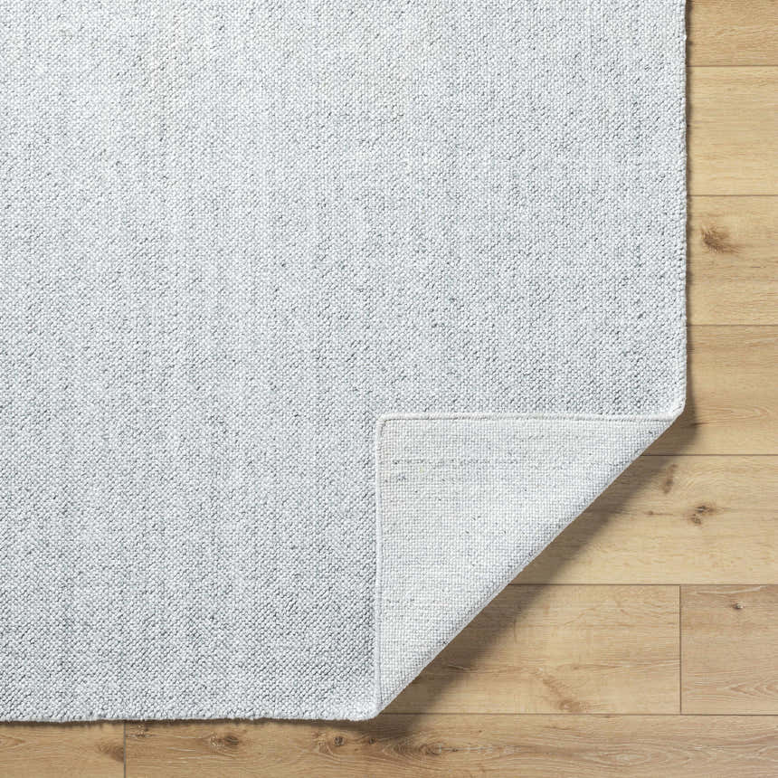 Close-up of the Zareh Gray Blue Solid Area Rug showing its light silver color and textured, hand-loomed construction. Fold