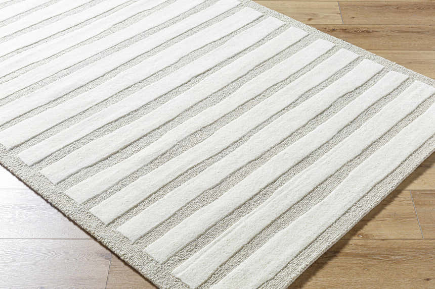 Close-up of the hand-tufted Zerah Area Rug. Ash and white wool rug with a contemporary striped design and textured look. Corner