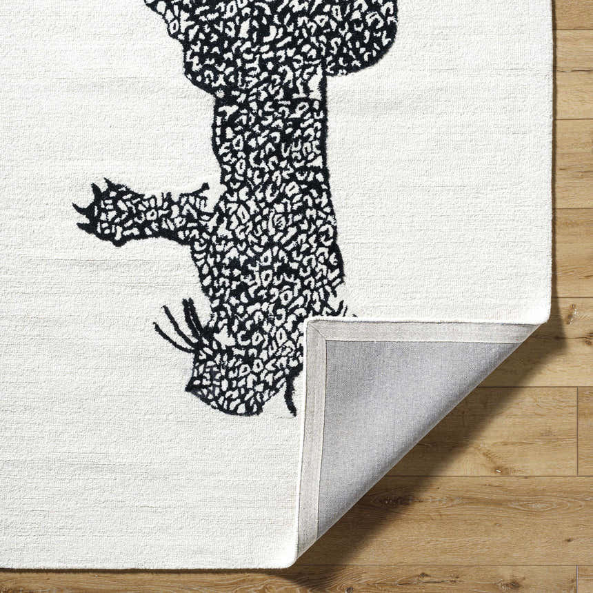 Close-up of the Zosia Area Rug, a hand-tufted wool rug with a black abstract design on an off-white background. Fold
