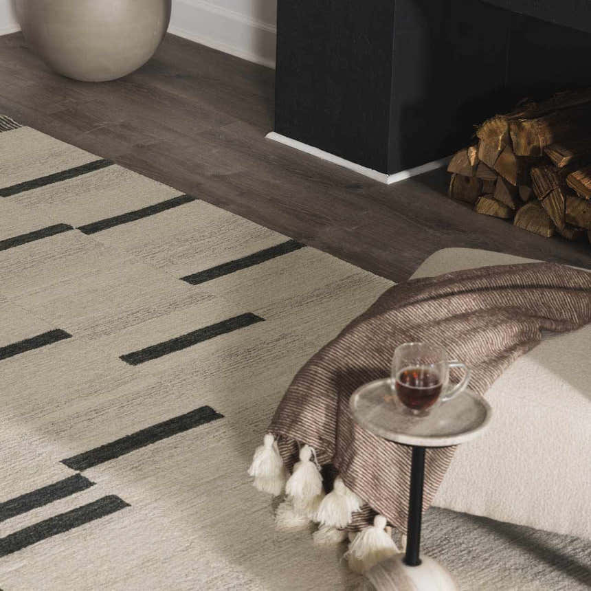 Living room scene with the beige Aibonito hand tufted wool rug, black accents, and a cozy fireplace. Roomscene-Rectangle