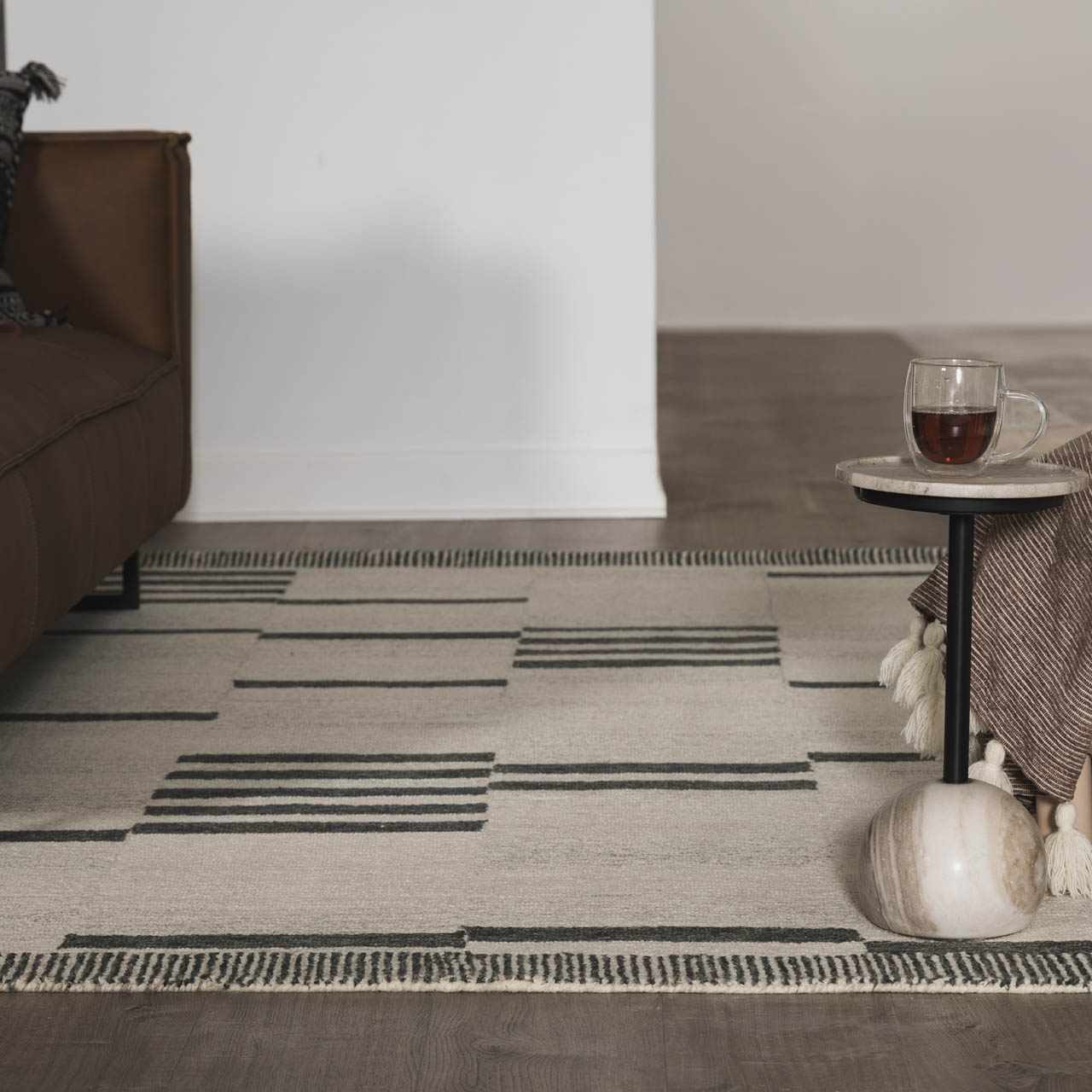 Living room scene with beige Aibonito Hand Tufted Wool Area Rug, brown couch, and marble side table. Modern, minimal style. Roomscene-Rectangle