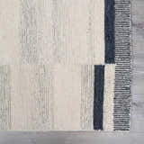 Close-up of the Aibonito hand tufted wool area rug featuring beige, gray, and black stripes. Wool texture visible. Swatch