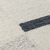 Close up of the Aibonito rug showing its beige wool texture and charcoal geometric pattern. Texture